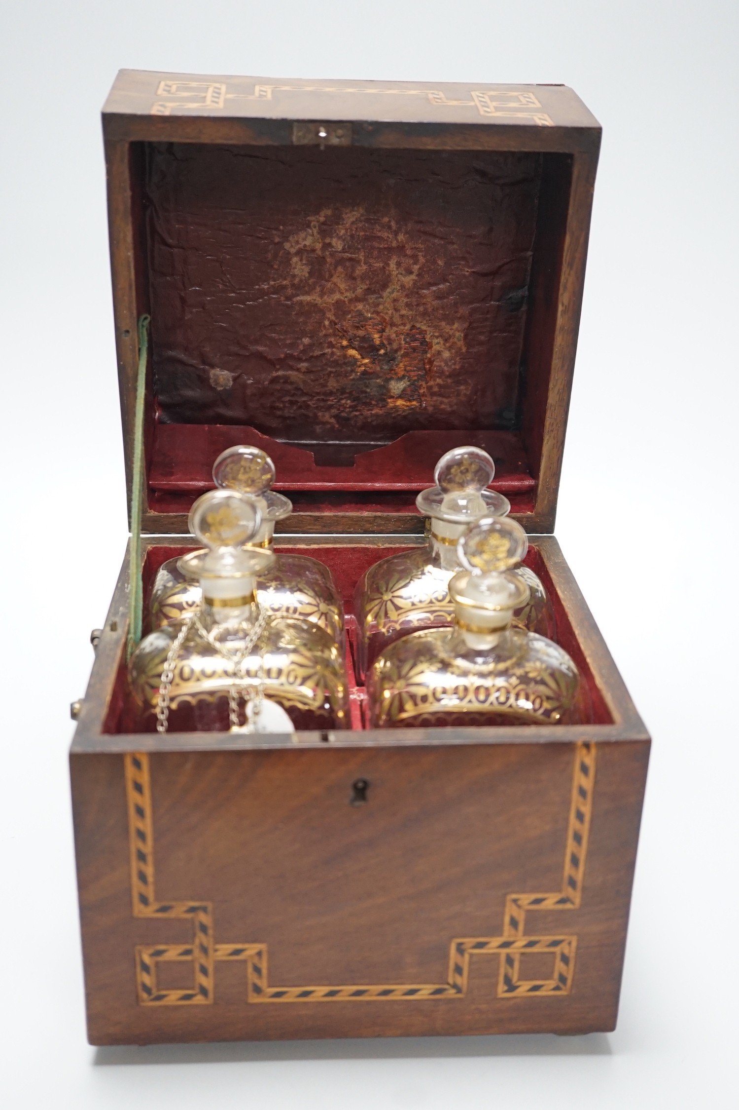 A George III inlaid mahogany decanter set with four gilt decorated decanters and two T.Goode & Co. enamelled wine labels, ‘BRANDY’ and ‘KÜMMEL’. 21cm tall